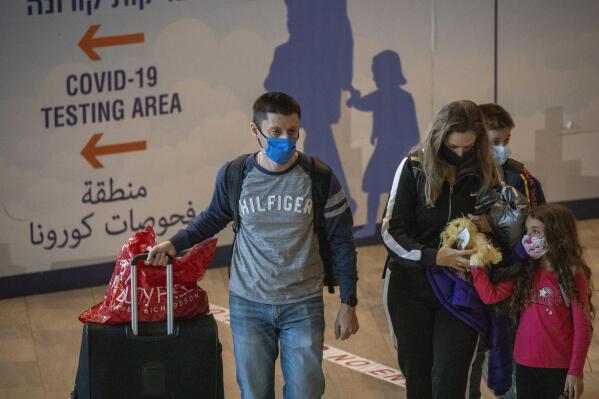 Travelers wearing protective face masks arrive at the Ben Gurion Airport near Tel Aviv, Israel, Sunday, Nov. 28, 2021. Israel on Sunday approved barring entry to foreign nationals and the use of controversial technology for contact tracing as part of its efforts to clamp down on a new coronavirus variant. (AP Photo/Ariel Schalit)
