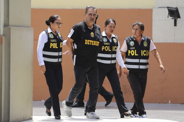 Officers escort Iranian Majid Azizi at police headquarters in Lima, Peru, Friday, March 8, 2024. (AP Photo/Manuel Castillo)