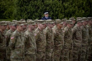 FILE - A Romanian policeman watches as U.S. military personnel attend a transfer of authority ceremony from the 101st Airborne Division to the 10th Mountain Division in Bucharest, Romania, Wednesday, April 5, 2023. U.S. troops are deployed to Romania along with forces from other NATO member states as the alliance looks to boost security on its southeastern flank amid Russia's war in Ukraine. (AP Photo/Andreea Alexandru)