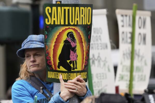 Cindy McPherson, with the Interfaith Movement For Human Integrity, listens to speakers during a news conference and rally by immigrant justice organizations and advocates to protest ICE arrests in San Francisco, Wednesday, May 28, 2025. (AP Photo/Jeff Chiu)