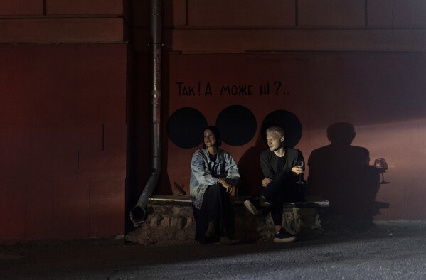 Oleh Khromov, the owner of Protagonist restaurant in Kharkiv, Ukraine, drinks wine with his wife Olena in the dark after the municipality temporarily cut the power to conserve energy, on Sunday, April 14, 2024. (AP Photo/Evgeniy Maloletka)