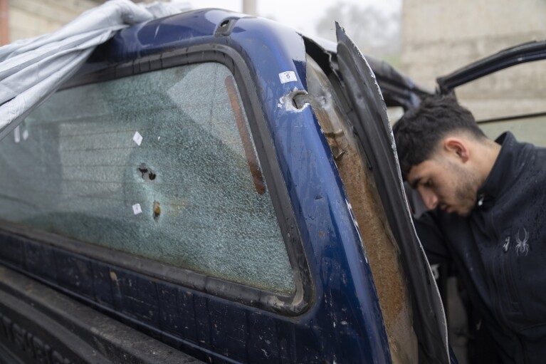 A young man inspects a damaged truck with bullet holes bearing an Israeli investigative tag in al-Majra ash-Sharqiya in the West Bank, Tuesday, Jan. 23, 2024.  Taufik Abdel Jabbar, a Louisiana teenager, was fatally shot while driving.  Truck on January 19th.  (AP Photo/Nasser Nasser)