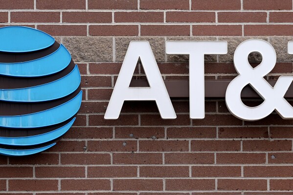 FILE - The company logo hangs over the door to an AT&T store Thursday, Feb. 22, 2024, in Denver. AT&T says it will give affected customers $5 each to compensate for last week's cellphone network outage that left many without service for hours.(AP Photo/David Zalubowski, File)