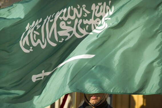 FILE - In this March 22, 2018, file photo, an honor guard member is covered by the flag of Saudi Arabia, in Washington. Saudi Arabia, for years one of the world's most prolific executioners, dramatically reduced the number of people put to death in 2020, following changes halting executions for non-violent drug-related crimes, according to the government’s tally and independent observers. (AP Photo/Cliff Owen, File)