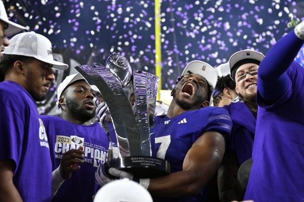 Washington running back Dillon Johnson holds the trophy after Washington defeated Oregon in the Pac-12 championship NCAA college football game Friday, Dec. 1, 2023, in Las Vegas. (AP Photo/David Becker)