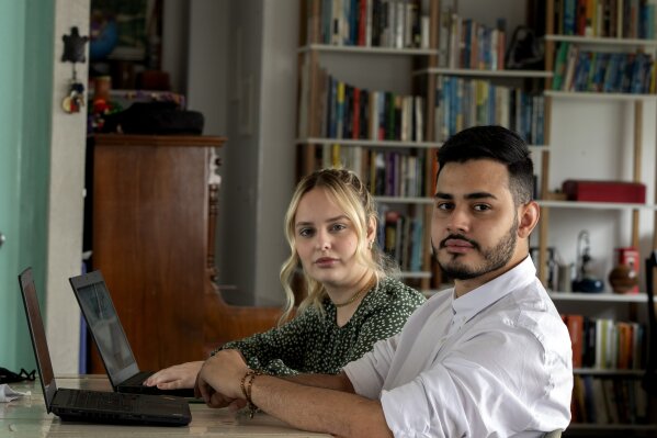Leonardo de Carvalho Leal, right, and Mayara Stelle, who administer the Twitter account Sleeping Giants Brazil, use their computers in Sao Paulo, Brazil, Friday, Dec. 11, 2020. Sleeping Giants is a platform for activism whose stated mission is to attack the financing of hate speech and dissemination of fake news. (AP Photo/Andre Penner)