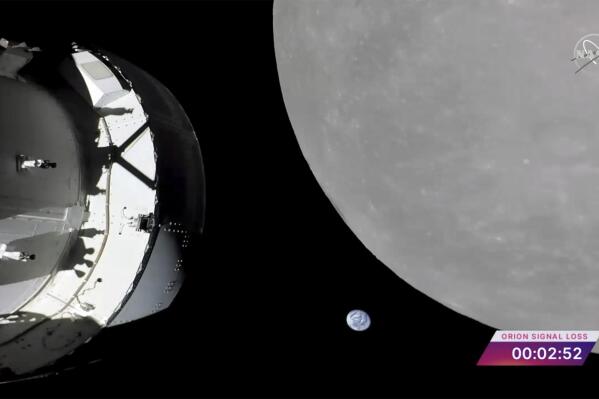 This screengrab from NASA TV shows NASA's Orion capsule, left, nearing the moon, right, Monday, Nov. 21, 2022. At center is earth. (NASA via AP)