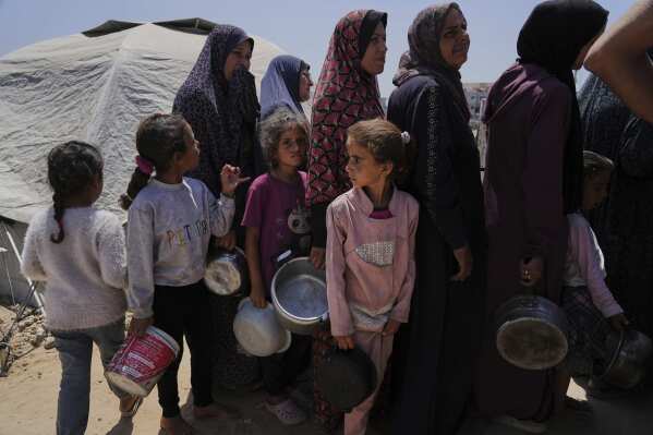 Displaced Palestinians line up to receive donated meals from a community kitchen at a tent camp in Gaza City on Wednesday, May 21, 2025. (AP Photo/Jehad Alshrafi)