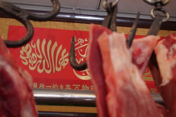 
              In this Dec. 7, 2018, photo, an Arabic inscription reading "there is no god but God" is hung in a butcher shop in the Islamic neighborhood of Niujie in Beijing, China. The shop's owner, Ma Changli, 39, said his people, China's second-largest Muslim ethnic minority group, the Hui, are supported but the central government despite reports of increasing crackdown on religious groups across the country in 2018. "Our country has always been pretty supportive to our worship," the butcher said. (AP Photo/Sam McNeil)
            