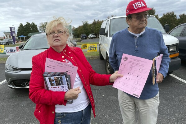 Dale Swanson, chair of the Spotsylvania County GOP, displays an official GOP sample ballot she was handing out at an early voting location in Fredericksburg, Va., on Oct. 17, 2023, while lamenting a campaign that is seeing "dirty tricks being played all over the place." She and Democrats alike were upset that a candidate for Spotsylvania County clerk of court was distributing sample ballots that resembled those of the parties, until a judge barred him from doing so. Swanson said civility is lacking in many races for local offices, including school boards, and "we need a better, kinder America." (AP Photo/Cal Woodward)