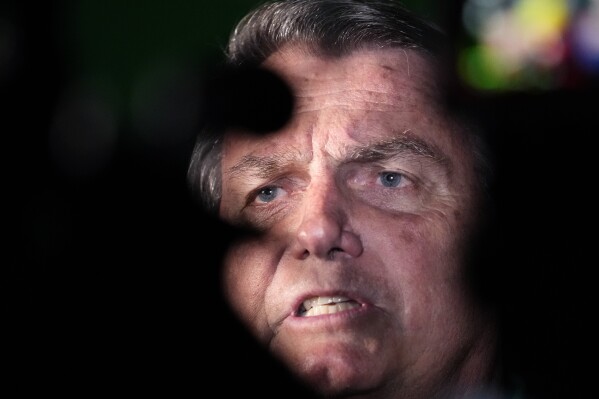 FILE - Former President Jair Bolsonaro talks to reporters after arriving at the airport in Brasilia, Brazil, Friday, June 30, 2023. Bolsonaro denied on Thursday, Sept. 21, a report claiming he had consulted top military leaders to stage a coup and stop his successor Luiz Inácio Lula da Silva from taking office in January.(AP Photo/Eraldo Peres, File)