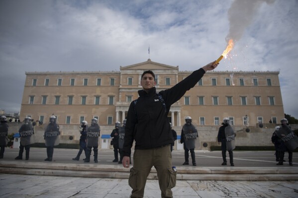 A student holds a flare during a protest in Athens, Greece, Thursday, Jan. 25, 2024. Several thousand university students and supporters took part in a protest in the Greek capital to oppose plans by Greece's conservative government to allow privately-run universities. (AP Photo/Michael Varaklas)