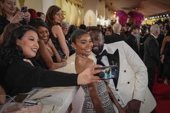 Gabrielle Union, left, and Dwayne Wade pose for a selfie at the Oscars on Sunday, March 10, 2024, at the Dolby Theatre in Los Angeles. (AP Photo/John Locher)