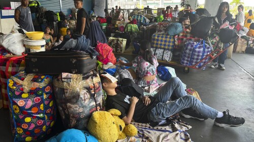 In this photo provided by the Philippine Coast Guard, stranded passengers stay at passenger terminal after sea travel was suspended due to Typhoon Doksuri in Manila, Philippines on Tuesday July 25, 2023. The powerful typhoon blew closer to the northern Philippines on Tuesday, forcing thousands of evacuations and a halt to sea travel ahead of torrential rains and tidal surges up to 3 meters (nearly 10 feet). (Philippine Coast Guard via AP)