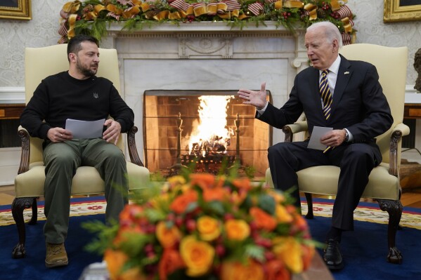 FILE - President Joe Biden reaches out to shake hands with Ukrainian President Volodymyr Zelenskyy as they meet in the Oval Office of the White House, Tuesday, Dec. 12, 2023, in Washington. The White House says funding for Ukraine has run out and it has been increasing pressure on Congress to pass stalled legislation to support the war against Russia. On Tuesday, however, Biden touted a new military aid package worth $200 million for Ukraine. That may seem contradictory, but it’s due to the complex programs used to send aid to Ukraine. (AP Photo/Evan Vucci, File)
