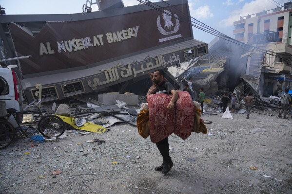 Palestinians walk past the Al Nuseirat Bakery, destroyed in an Israeli airstrike, in Nusseirat refugee camp Gaza Strip, Wednesday, Oct. 18, 2023. (AP Photo/Hatem Moussa)