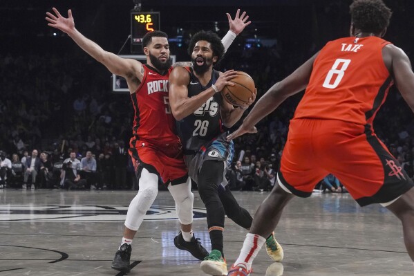 Brooklyn Nets' Spencer Dinwiddie, center, split the defense of Houston Rockets' Fred VanVleet, left, and Jae'Sean Tate during the second half of an NBA basketball game Saturday,Jan. 27, 2024, in New York. (AP Photo/Bebeto Matthews)