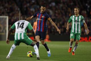Barcelona's Sergio Busquets, center, is challenged by Betis' William Carvalho, left, and Betis' Sergio Canales during a Spanish La Liga soccer match between Barcelona and Real Betis at the Camp Nou stadium in Barcelona, Spain, Saturday, April 29, 2023. (AP Photo/Joan Monfort)