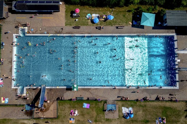 People spend time in a public pool in Wehrheim near Frankfurt, Germany, on a hot Saturday, July 8, 2023. (AP Photo/Michael Probst)