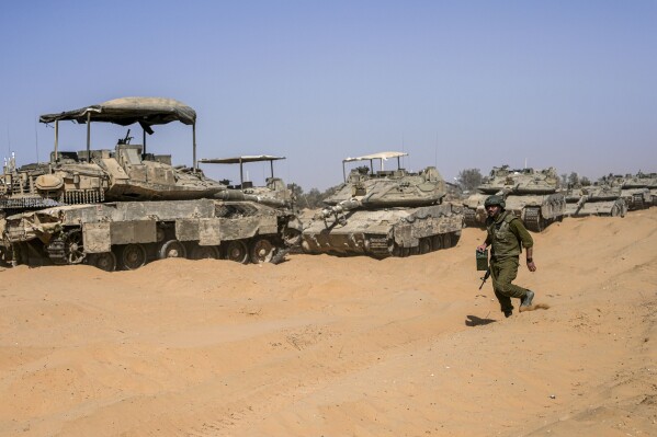 An Israeli soldier walks past a line of tanks at a staging ground near the border with the Gaza Strip, in southern Israel, Sunday, May 5, 2024. (AP Photo/Tsafrir Abayov)