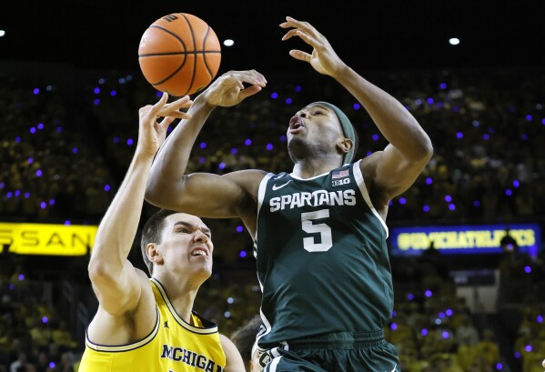 Michigan State guard Tre Holloman (5) has the ball knocked away by Michigan center Vladislav Goldin (50) during the first half of an NCAA college basketball game Friday, Feb. 21, 2025, in Ann Arbor, Mich. (AP Photo/Duane Burleson)