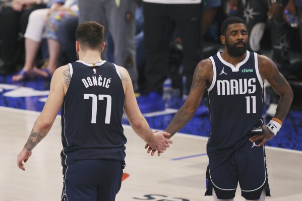 Dallas Mavericks guard Luka Doncic (77) shakes hands with teammate Kyrie Irving (11) after their loss to the Minnesota Timberwolves in Game 4 of the NBA basketball Western Conference finals, Tuesday, May 28, 2024, in Dallas. (AP Photo/Gareth Patterson)