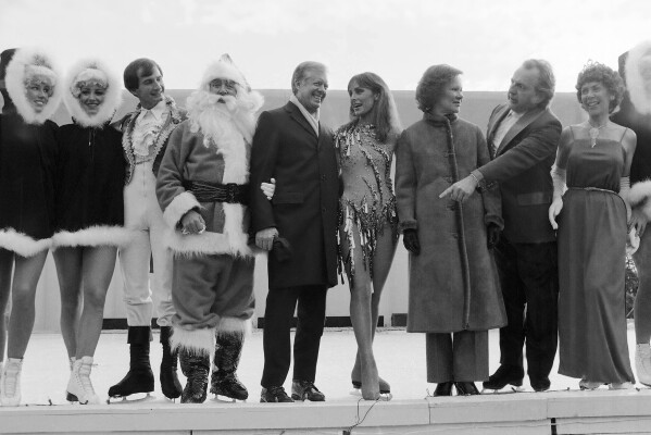 FILE - President Jimmy Carter calls on other entertainers to join him, Santa Claus and ice skating star Peggy Fleming for photos at a White House reception for U.S. Secret Service agents and military aides in Washington, December 22, 1980. Jill Biden is bringing a holiday skating rink to the White House lawn so children can skate and play hockey during the holidays.  The first lady was expected to announce the construction of the rink Wednesday after sunset.  She was to be joined by, among others, 1988 Olympic figure skater Brian Boitano and the character Snoopy.  The White House says the rink will be operating in December.  (AP Photo/Dennis Cook, file)