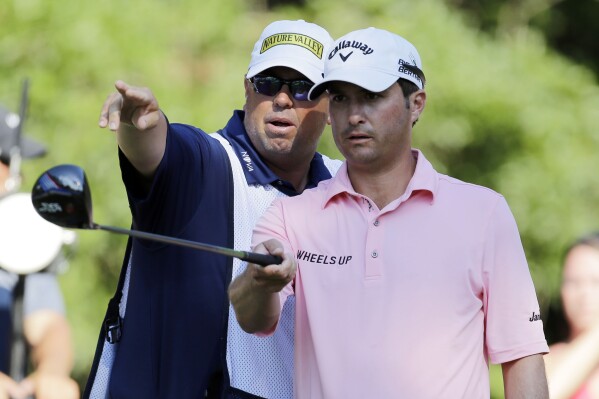FILE - Kevin Kisner, right, listens to his caddie Duane Bock, before hitting on the 15th tee during the third round of The Players Championship golf tournament on May 9, 2015, in Ponte Vedra Beach, Fla. The American caddie will be part of Team Europe when he works for Sepp Straka of Austria in the Ryder Cup in Italy. (AP Photo/Chris O'Meara, File)