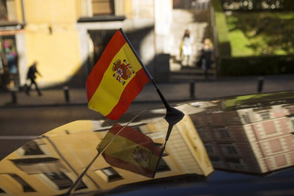 
              People walk past by a car with a Spanish flag attached on top in Madrid, Tuesday, Oct. 24, 2017. Spain's Senate is expected to greenlight Rajoy’s plan on Friday, triggering previously untapped constitutional powers to act against regional leaders disobeying the country’s top law. (AP Photo/Francisco Seco)
            