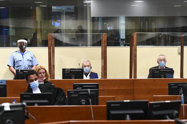Former head of Serbia's state security service Jovica Stanisic, centre, and his subordinate Franko "Frenki" Simatovic, right, appear in court at the UN International Residual Mechanism for Criminal Tribunals (IRMCT) in The Hague, Netherlands, Wednesday June 30, 2021.  A UN court is delivering judgments in the retrial of Jovica Stanisic and Franko Simatovic, accused of organizing, arming and supporting Serb paramilitaries that committed atrocities in Croatia and Bosnia as Yugoslavia crumbled in the early 1990s.  (Piroschka van de Wouw/Pool via AP)