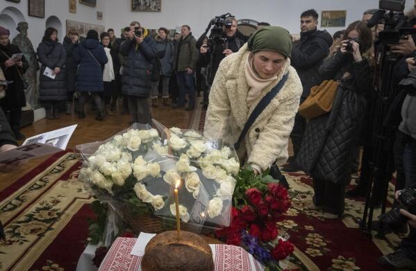 People lay flowers to commemorate British volunteers Chris Parry and Andrew Bagshaw, killed in Ukraine's war-hit east, during commemorating service in a refectory near St. Sophia Cathedral in Kyiv, Ukraine, Sunday, Jan. 29, 2023. Andrew Bagshaw was a dual New Zealand and British citizen who was killed along with British colleague Chris Parry while attempting to rescue an elderly woman from the town of Soledar when their car was hit by an artillery shell. (AP Photo/Efrem Lukatsky)