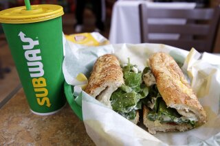 FILE - In this Friday, Feb. 23, 2018 file photo, the Subway logo is seen on a soft drink cup next to a sandwich at a restaurant in Londonderry, N.H.. Ireland’s Supreme Court has ruled that bread sold by the fast food chain Subway contains so much sugar that it cannot be legally defined as bread. (AP Photo/Charles Krupa, File)