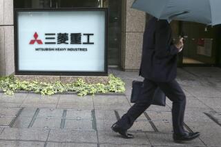 FILE - A man walks past the company sign of the Mitsubishi Heavy Industries in Tokyo Tuesday, July 16, 2019. Mitsubishi Heavy Industries and the Japan Atomic Energy Agency have signed an agreement, Wednesday, Jan. 26, 2022, to participate in a next-generation nuclear energy project with TerraPower, a company started by Bill Gates. (AP Photo/Koji Sasahara, File)