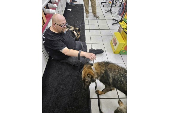 In this photo provided by the Humane Society of Hobart, Ind., a dog suffering from heat-related injury is aided by a man inside the Road Ranger convenience store, in Lake Station, Ind., July 27, 2023. (Jennifer Webber/Humane Society of Hobart, Ind. via AP)
