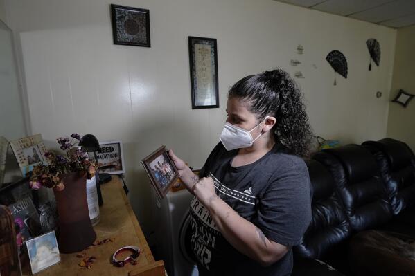 Roxanne Schaefer holds a photograph in the living room of her apartment, in West Warwick, R.I., Tuesday, July 27, 2021. Schaefer, who is months behind on rent, is bracing for the end to a CDC federal moratorium Saturday, July 31, 2021, a move that could result in millions of people being evicted just as the highly contagious delta variant of the coronavirus is rapidly spreading. (AP Photo/Steven Senne)
