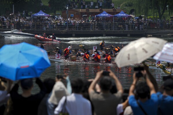 2024年6月10日，星期一，北京郊区通州的一条运河上，居民们在端午节期间观看龙舟比赛。端午节又称端午节，农历五月初五，以吃粽子和赛龙舟为标志。（美联社照片/王安迪）