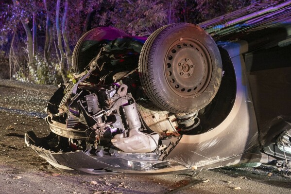 A car lays on the road after an accident near Kiskunmajsa, Hungary, Thursday, Oct. 12, 2023. Two people were killed and six other injured in a car accident in Hungary early Thursday after a vehicle suspected of transporting illegal migrants hit a tree and overturned. (AP Photo/Ferenc Donka)