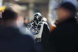 FILE - In this March 15, 2013 file photo a woman with a headscarf, a traditional dress for Islamic women, walks between other people on a street at the district Neukoelln in Berlin. The European Union’s top court ruled Thursday that employers may forbid the wearing of visible symbols of religious or political belief, such as headscarves.  (AP Photo/Markus Schreiber)