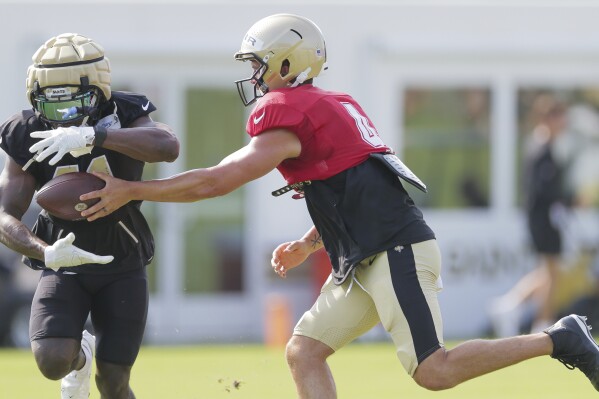 New Orleans Saints quarterback Derek Carr (4) hands the ball to Saints running back Alvin Kamara (41) during a drill at NFL football training camp practice in Metairie, La., Monday, July 31, 2023. (David Grunfeld/The New Orleans Advocate via AP)