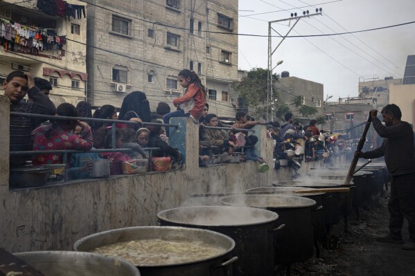 Palestinians line up for a free meal in Rafah, Gaza Strip, Thursday, Dec. 21, 2023. International aid agencies say Gaza is suffering from shortages of food, medicine and other basic supplies as a result of the two and a half month war between Israel and Hamas. (AP Photo/Fatima Shbair)