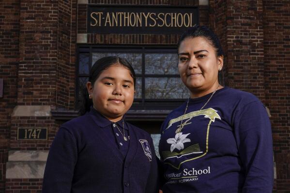 Lorena Ramirez poses with her daughter Citlalli outside St. Anthony School Thursday, Oct. 20, 2022, in Milwaukee. School choice allows taxpayer money to pay for private school tuition instead of only financing public schools. “It’s a huge difference because it’s a support in faith and in values,” said Ramirez, whose four children attend St. Anthony, walking distance from home on Milwaukee's south side. (AP Photo/Morry Gash)