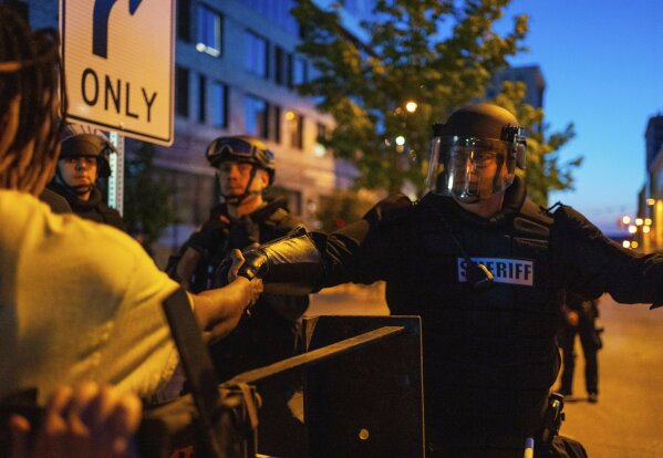 Protesters shake hands with sheriff's deputies to end their march against police brutality, Wednesday, June 3, 2020, in Grand Rapids, Mich. A deputy kneeled after protesters asked at least one officer or deputy to kneel in solidarity. (Anntaninna Biondo/The Grand Rapids Press via AP)