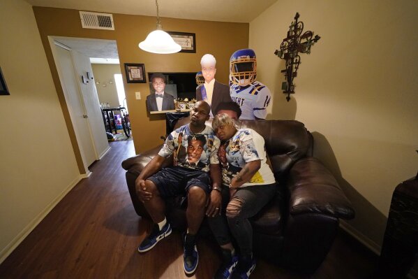 Kevin and Rontunda Moran, who lost their 17-year-old son, Jaquan Anderson, to the coronavirus, pose with T-shirts bearing his likeness, and cardboard cutouts of him in their home in New Orleans, Wednesday, Oct. 14, 2020. Jaquan was getting ready for his senior year in high school and all the milestones that mark the beginning of adulthood — getting his driver's license, voting and heading to college. He died March 22, one of the youngest victims of the coronavirus that has largely taken the lives of older people. (AP Photo/Gerald Herbert)