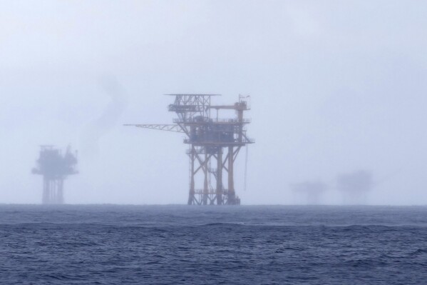 CORRECTS TO 382 MILLION NOT 328 FILE - Oil platforms are visible through the haze near the Flower Garden Banks National Marine Sanctuary in the Gulf of Mexico, off the coast of Galveston, Texas, Sept. 16, 2023. Oil companies offered $382 million for drilling leases in the Gulf Wednesday after courts rejected the Biden administration's plans to scale back the sale to protect an endangered whale species. (AP Photo/LM Otero, file)