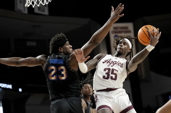 Texas A&M guard Manny Obaseki (35) shoots past Memphis forward Malcolm Dandridge (23) during the first half of an NCAA college basketball game Sunday, Dec. 10, 2023, in College Station, Texas. (AP Photo/Sam Craft)