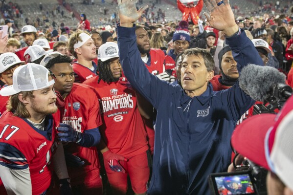 Liberty coach Jamey Chadwell celebrates with players after a win over New Mexico State in the Conference USA championship NCAA college football game Friday, Dec. 1, 2023, in Lynchburg, Va. (AP Photo/Robert Simmons)