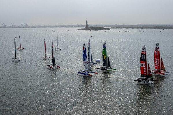 In this aerial image provided by SailGP, the fleet races at the start of Fleet Race One, with a view of the Statue of Liberty in the distance, on Day 1 of the New York Sail Grand Prix sailing races, Saturday, June 22, 2024, in New York. (Simon Bruty/SailGP via AP)