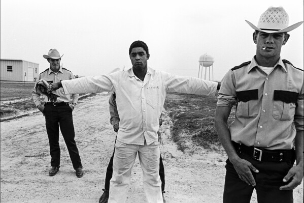 In this 1973 photo, three guards shake down and body search a prisoner and at the Cummins Unit of' Arkansas Department of Corrections in Grady, Ark. (Bruce Jackson via AP)