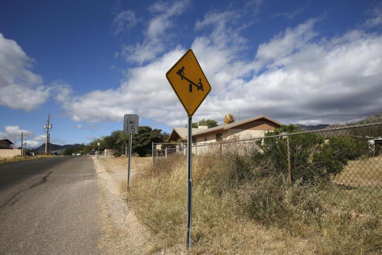 A “playground ahead” warning stands by the side of a road on the outskirts of Bisbee, Ariz., Oct. 26, 2021. Bisbee was home to Paul and Leizza Adams, and their six children, before Paul and Leizza were charged with child sexual abuse. (AP Photo/Dario Lopez-Mills)