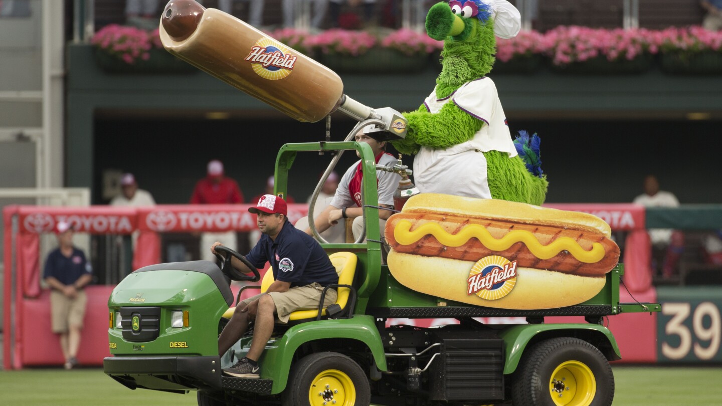 FILE - The Phillie Phanatic comes out with his Hot Dog Launcher during the fifth inning of a baseball game between the Atlanta Braves and the Philadelphia Phillies, Monday, July 4, 2016, in Philadelphia. For more than a quarter-century, Phillies fans thought dollar hot dog night was the best ballpark promotion — but the team has now decided it was the wurst. (AP Photo/Chris Szagola, File)
